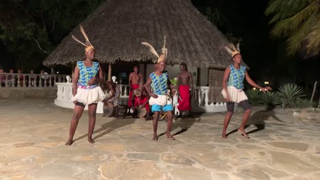 female black dancers entertaining guests with traditional cultural dance performance. ethnic dancing before hut at hotel at night. evening dances entertaining guests to the beat of drums.