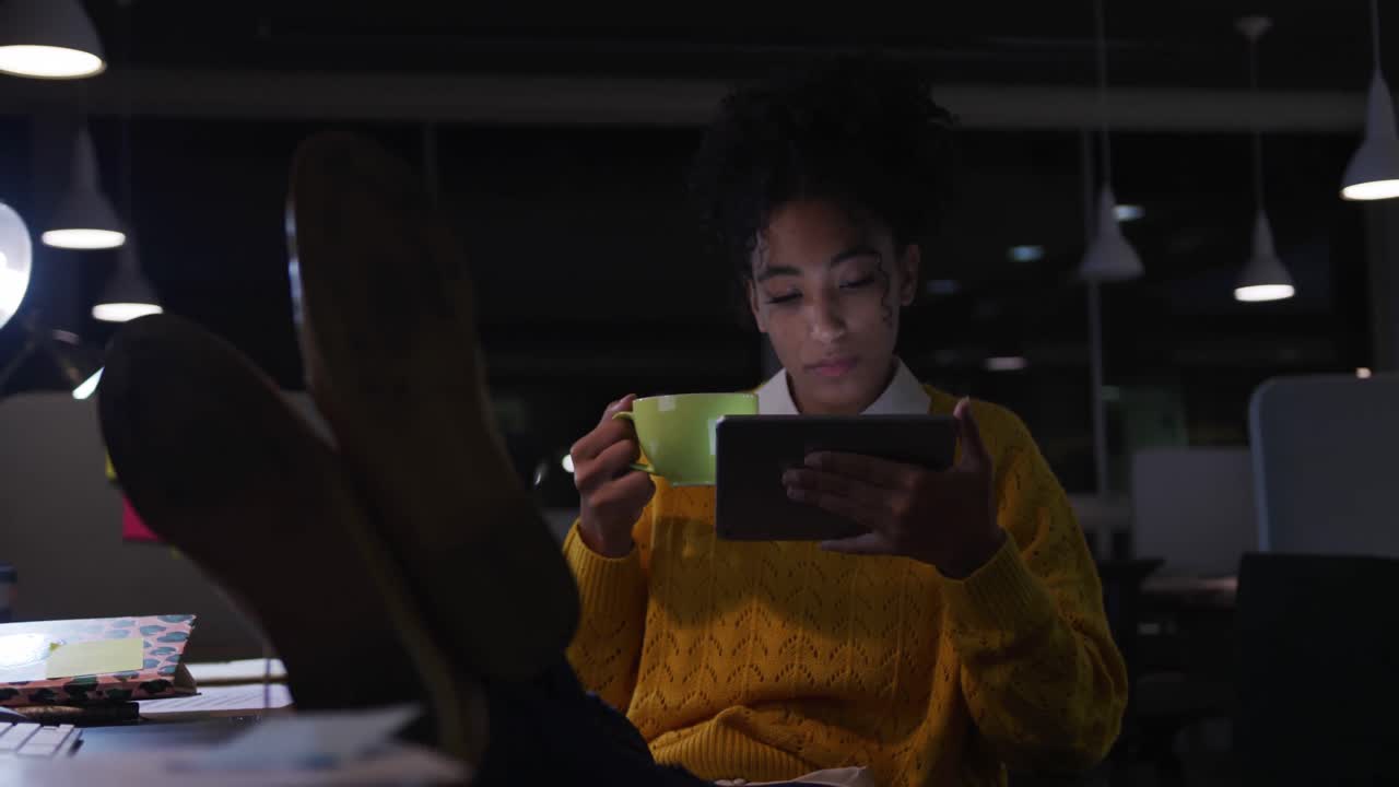 Businesswoman drinking coffee and working in a modern office by night