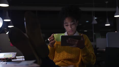 businesswoman drinking coffee and working in a modern office by night
