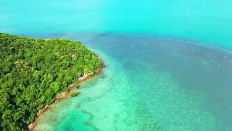 beautiful coral reefs barrier under turquoise lagoon surrounding rocky coastline of tropical island cape with green vegetation, thailand