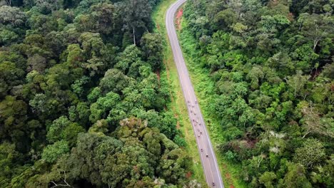 tourists riding motorcycles in the hills of chogoria with lush vegetation in kenya - aerial drone shot