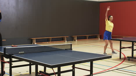 playing table tennis, woman in sportswear hitting ball in indoor gym