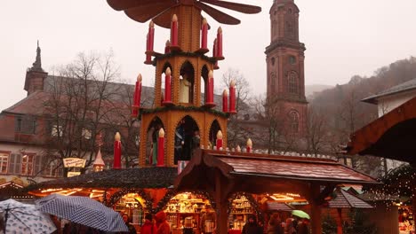 wooden pyramid spinning propellers in front of a church steeple in heidelberg, germany at a festive christmas market in europe