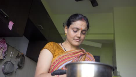 indian women in kitchen making tea and using mobile low angle shot