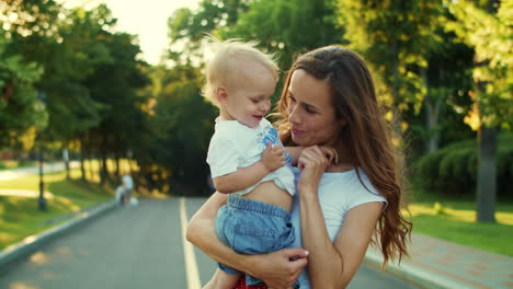 Mother-holding-kid-on-hands-in-park.-Woman-and-boy-playing-together-outdoors