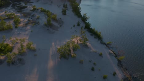 drone following the lakeshore and slowly revealing the sunset over sandbanks