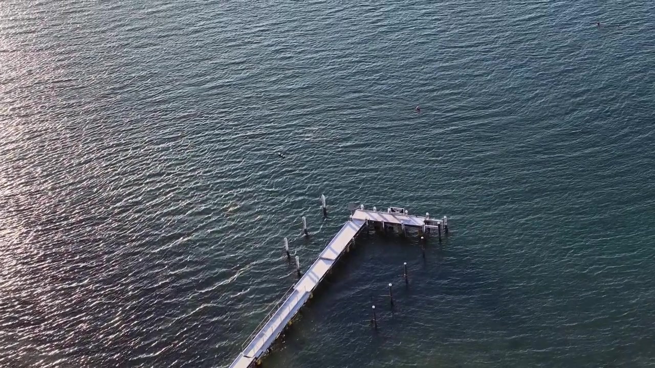 Aerial View of a Wooden Pier Extending into Calm Ocean Waters