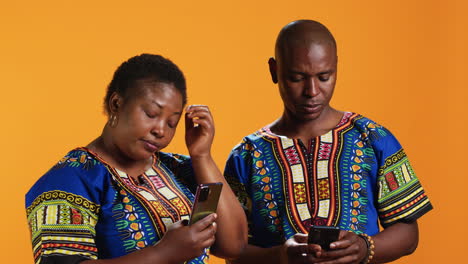 ethnic couple scrolling on social media accounts in studio