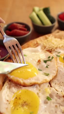 forkful of fried eggs on a breakfast pizza