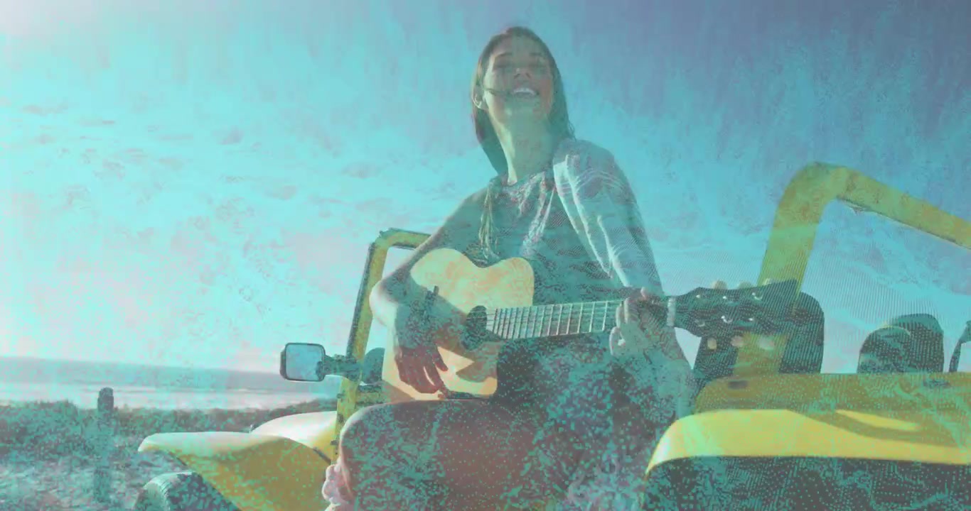 Musicista donna seduta su un buggy giallo, che inizia a strimpellare la chitarra acustica, cantando sulla spiaggia.