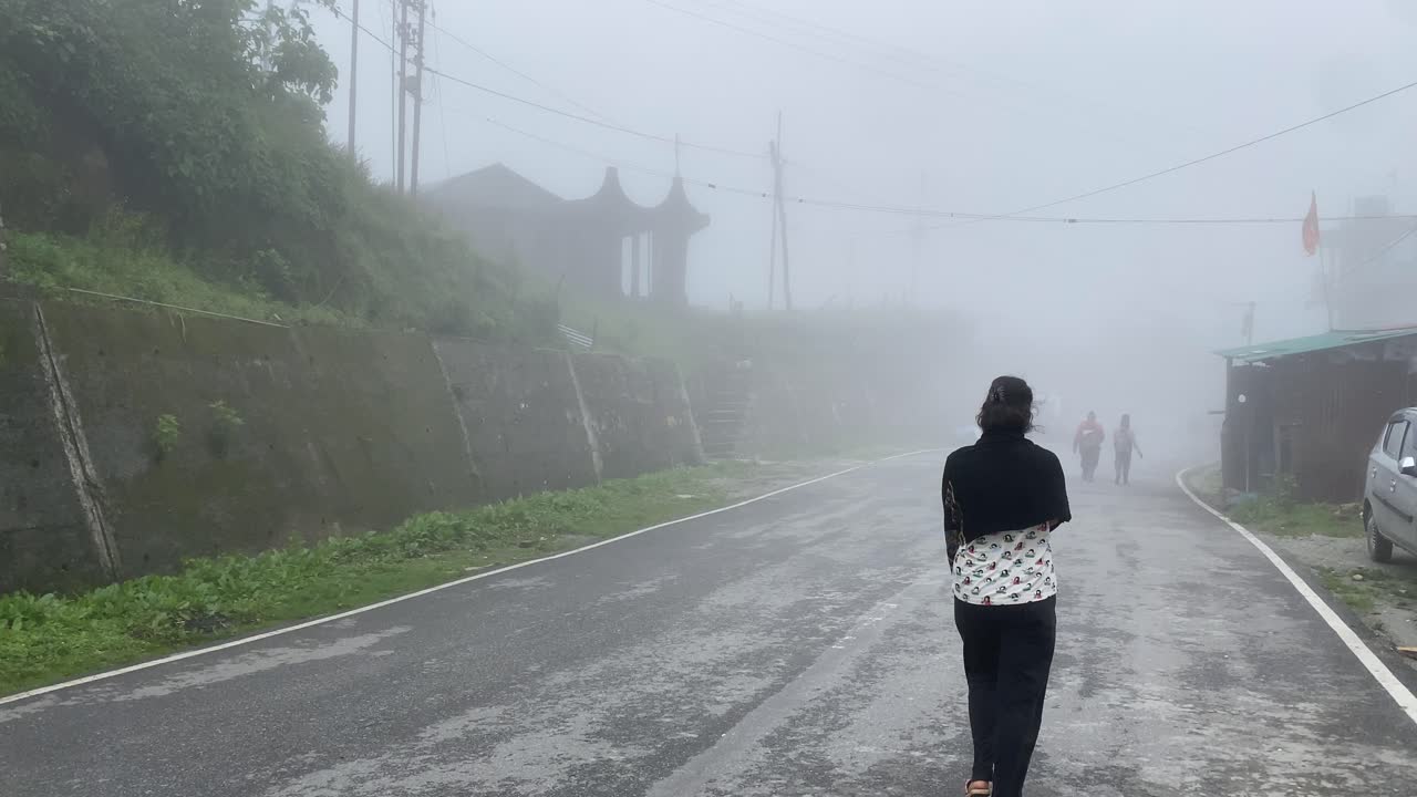 안개 낀 날 인도 언덕 꼭대기에서 산길을 걷는 행복한 젊은 인도 소녀의 뒷모습