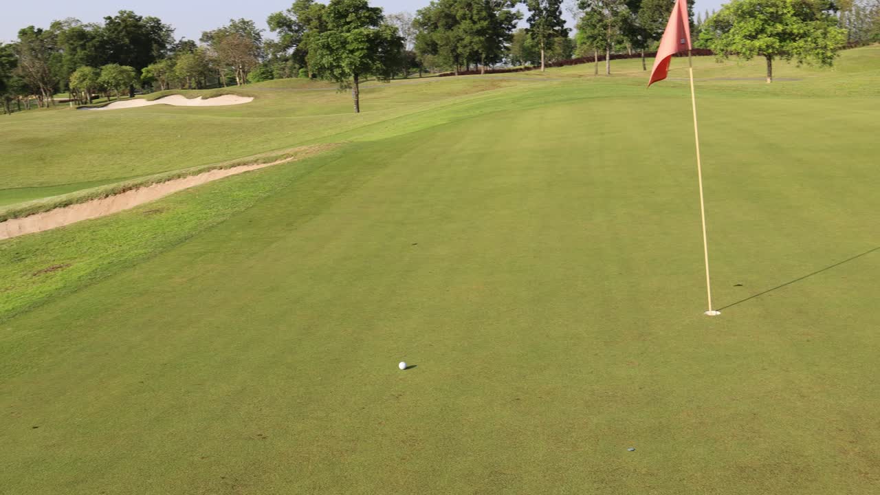 Golfer hits ball from sand bunker onto green