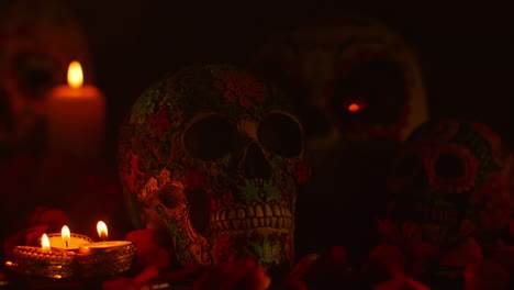 close up on still life of decorated skulls surrounded by candles and flower petals celebrating mexican holiday of dia de muertos or day of the dead 2