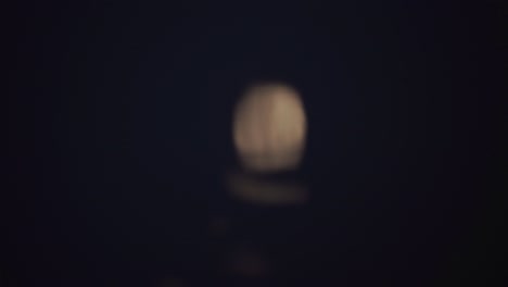 defocused bright moon reflecting on rippling lake water at night