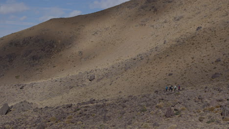 Trail-of-hikers-making-their-way-down-a-majestic-rocky-mountain-in-the-region-of-Marrakesh,-Morocco