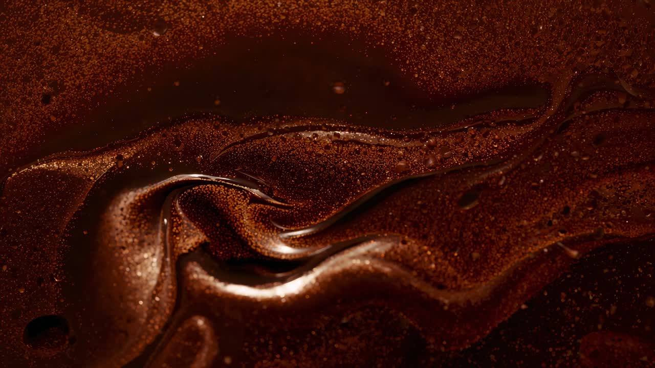 Rippling viscous chocolate surface folding, forming bubbles, shifting shine while cooling at studio