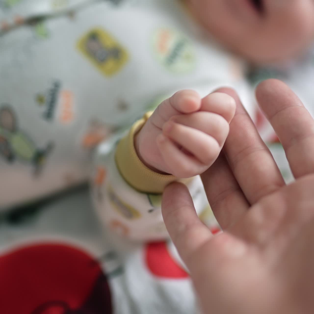 Father is taking tiny baby fist in his hand. Parent and baby interaction close up. Dad playing with toddler son
