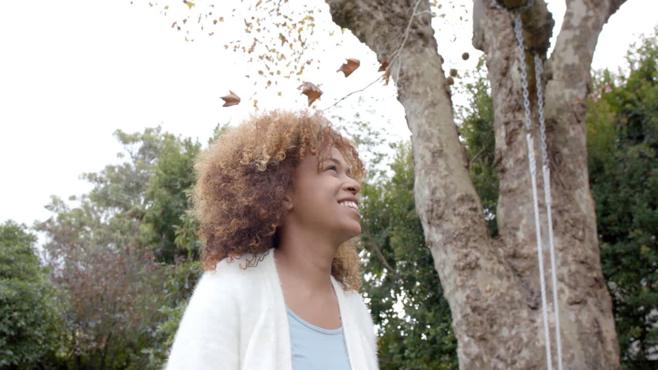 feliz mujer afroamericana sonriendo y caminando en el jardín, cámara lenta