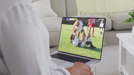 video de un hombre caucásico sentado en el sofá y viendo fútbol en la computadora portátil en casa
