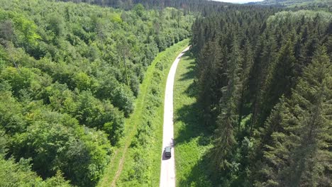 Disparo-De-Un-Dron-Siguiendo-Un-Coche-De-Un-Trabajador-Forestal-Por-Un-Sendero-En-El-Bosque-De-Verdún.-Francia