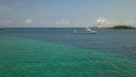 vista aérea alrededor de un yate que pasa por el faro de nassau, en las soleadas bahamas - dando vueltas, disparo de drones