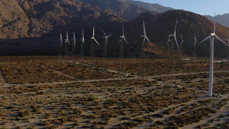 Aerial-view-of-drone-flying-towards-dozens-of-wind-turbines-in-the-desert-at-San-Gorgonio-Pass-wind-farm-near-Palm-Springs-in-the-Mojave-Desert,-California,-USA