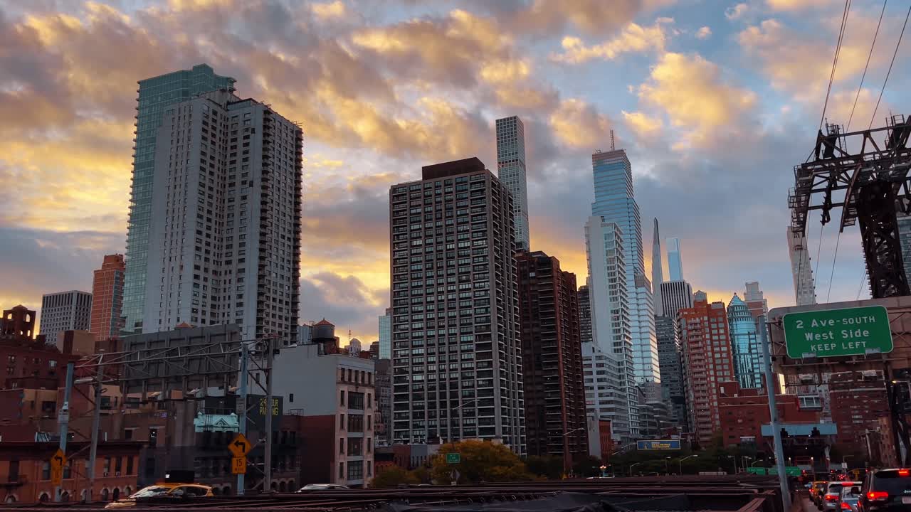 New York, USA, 2 marzo 2026: Grattacieli di Midtown Manhattan al tramonto con un segnale stradale. Vista dello skyline di New York City e del 432 Park Avenue da un ponte, con segnali stradali verdi in primo piano.
