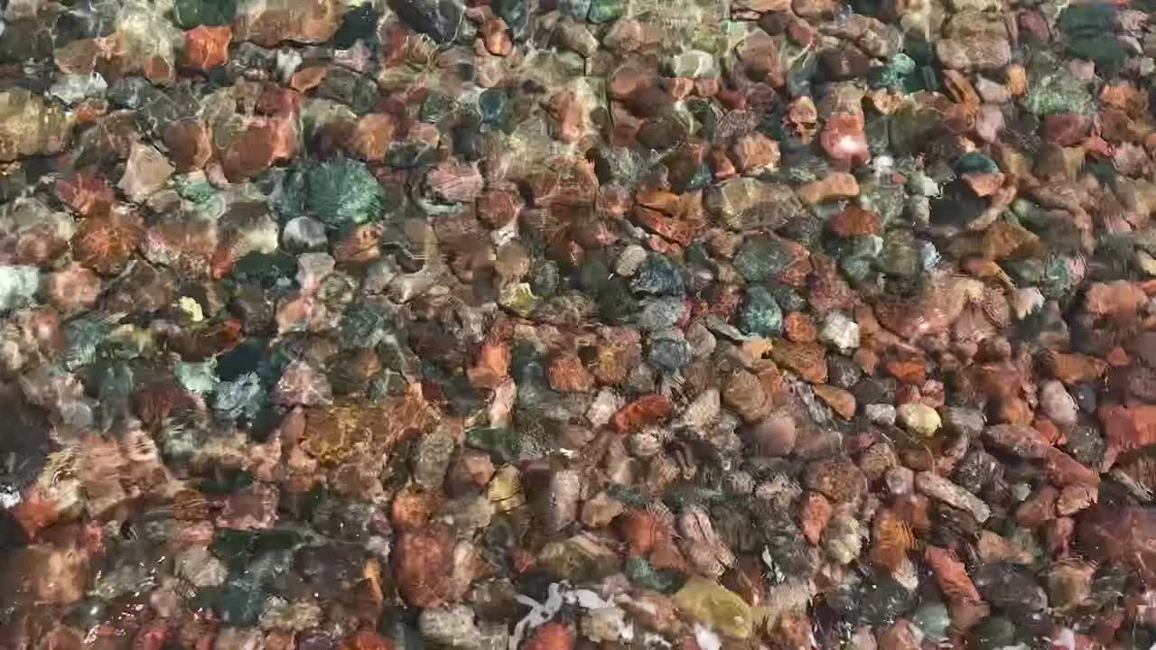 кристально прозрачная чистая вода волны на дне галька камни патерн фон