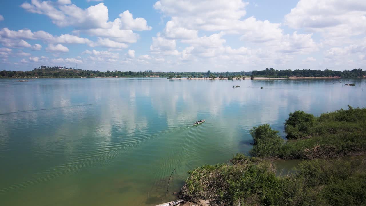 메콩 강 무인 항공기는 라오스 캄보디아 국경의 푸른 하늘 수평선에 물결 모양의 반사와 푹신한 구름으로 페리 보트를 따라갑니다.