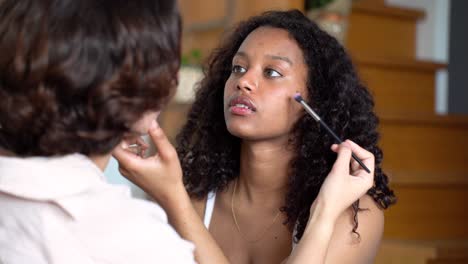 side view of young diverse friends applying makeup to each other