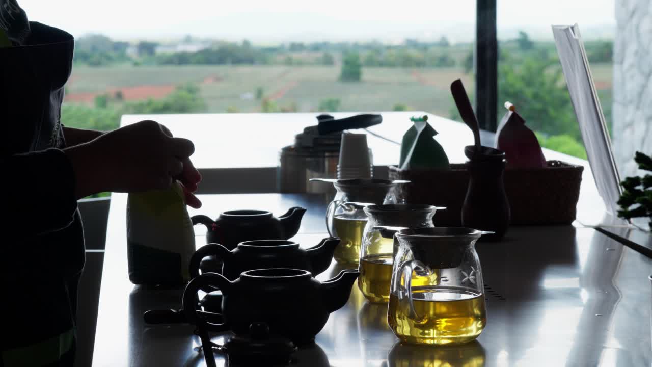 시골 풍경을 가진 차 서비스 설정: 노동자가 치앙라이 태국의 녹색 차 농장에서 잎을 비에 넣는 동안, 휴대용 백라이트 정적