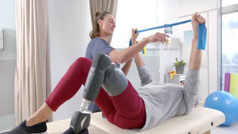fisioterapeuta caucásica y paciente mayor con prótesis de pierna ejercitándose