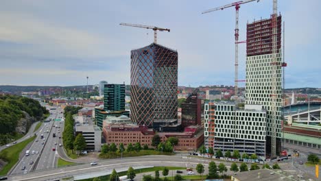 traffic driving in the road passing by citygate and kineum high-rise building under construction in gothenburg, sweden