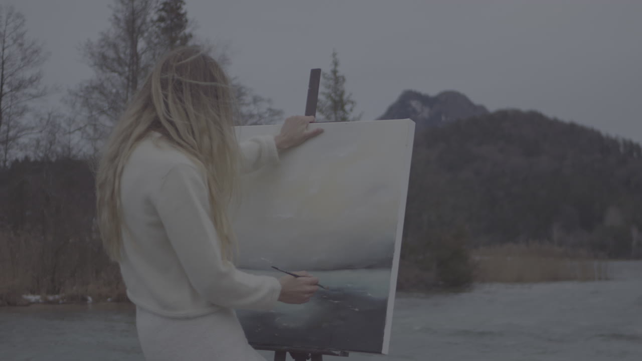 Woman Painting Outdoors by a Lake in Winter