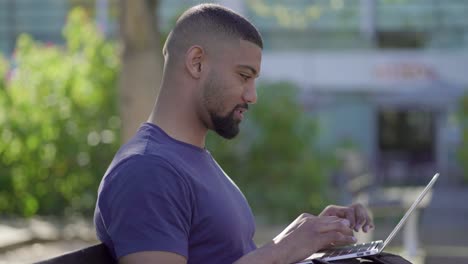 side view of man working on laptop, turning head to camera