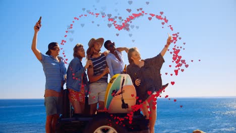 animación de corazones formando forma de corazón sobre amigos multirraciales tomando selfies contra el mar y el cielo