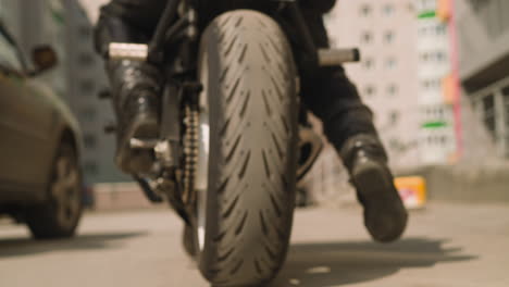 driver in moto suit rides motorcycle along parking site