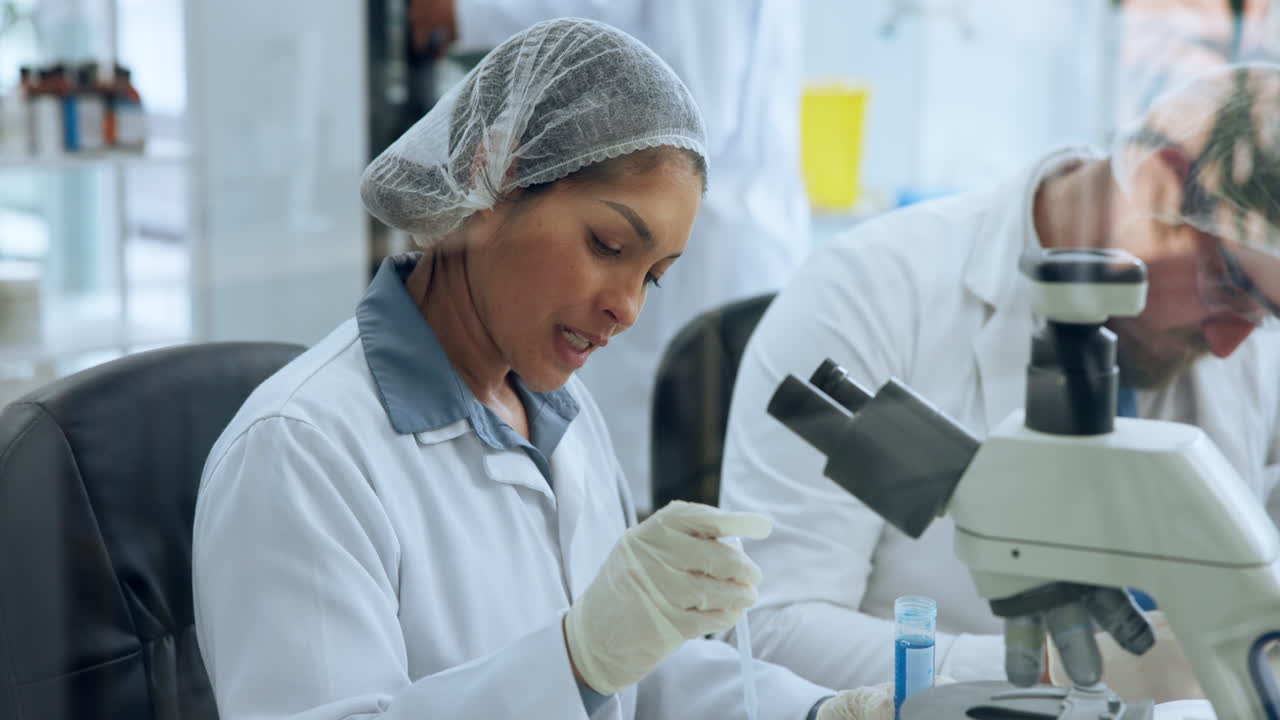 Female Scientist Working with Microscope and Pipette in a Laboratory