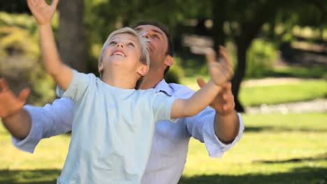 dad and his son playing with a soccer ball sitting on the grass