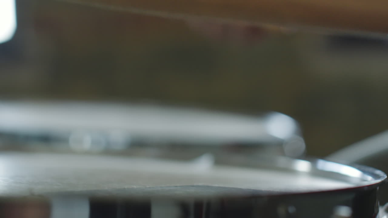 A close-up, blurry shot of a drumstick resting on a drum