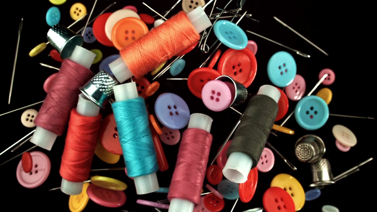 Colorful Sewing Supplies Falling in Slow Motion on Black Background