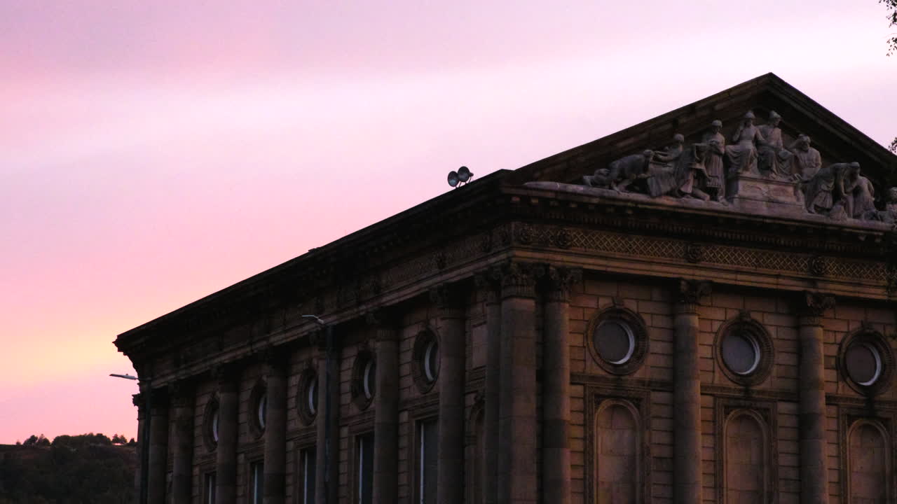 Todmorden Town Hall bathed in soft pink morning light as birds gracefully fly across the sky
