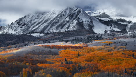 dramatic kebler pass crested butte colorado stunning fall winter first snow seasons collide aerial cinematic drone yellow aspen tree forest rocky mountains fog clouds lifting circle right motion