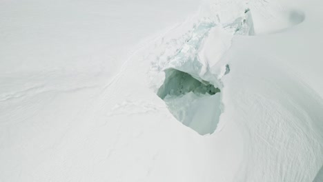 huge snow collapsed hollow on mountain slope, glacial cavern, avalanche hazard