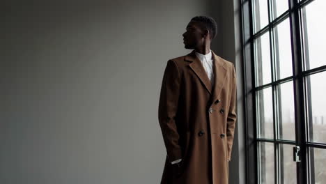 man in brown coat looking out window