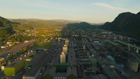 sunrise illuminating half norwegian industrial complex, remainder in shadow