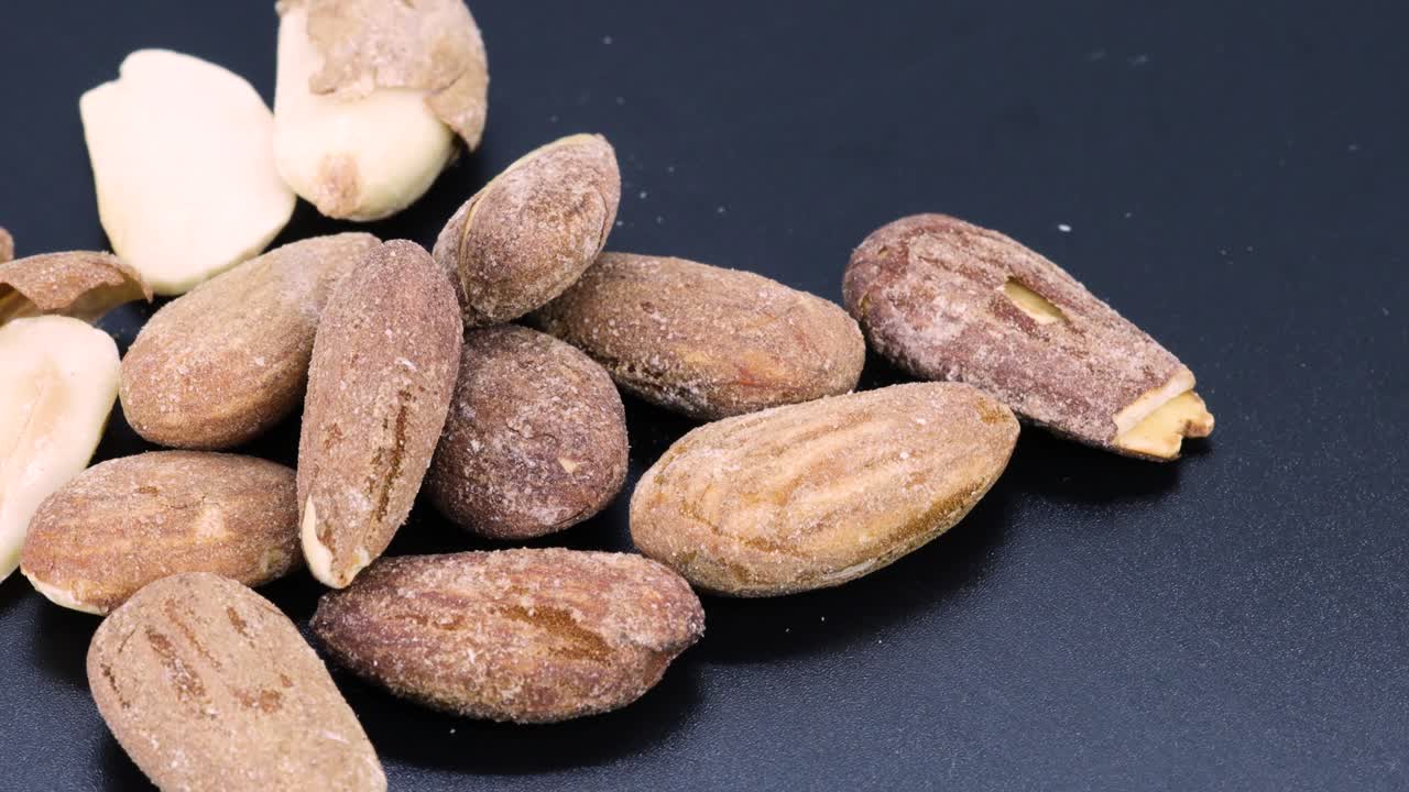 껍질과 소금을 곁들인 튀긴 천연 아몬드 한 다발을 회전하면서 클로즈업 샷