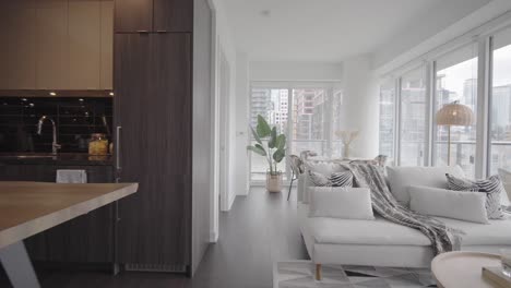 wide angle orbit push in shot from the kitchen and living area to dinning area and also shows the balcony and the bedroom through the door in a condominium unit