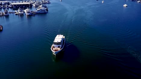 aerial,-reverse,-slow-tilt-up-to-reveal-boat-leaving-Gig-Harbor,-Washington,-US-on-a-bright-summer-day