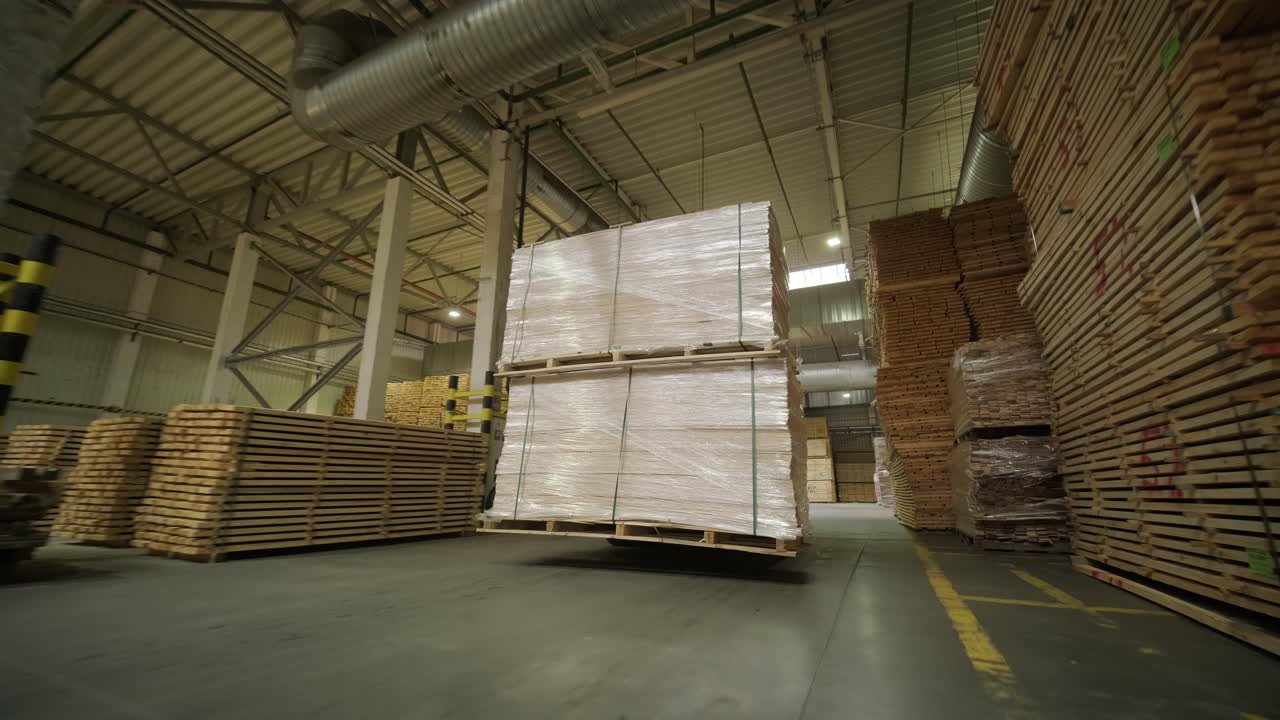 Carrello elevatore che sposta tavole di legno impilate su pallet in magazzino